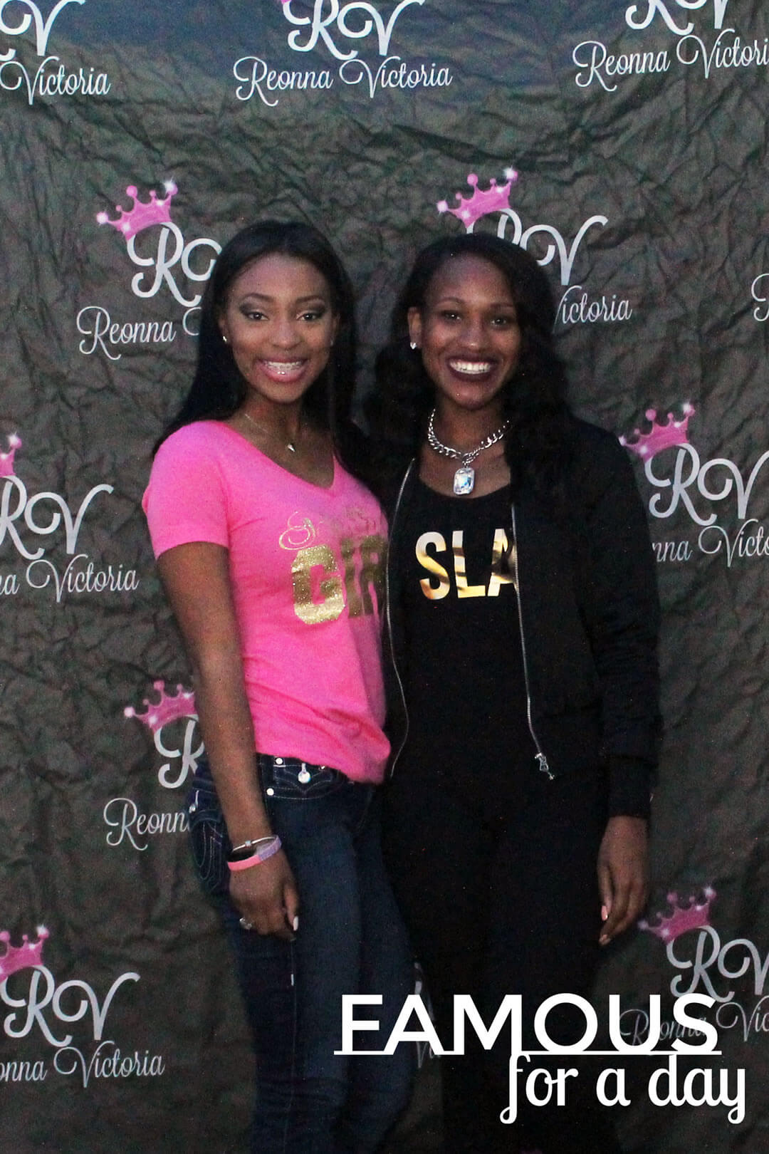 Two women posing together in front of a branded event backdrop while attending a red carpet experience